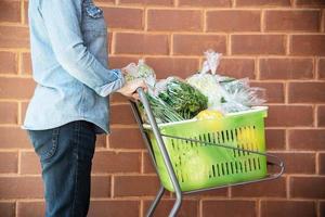 la señora está comprando verduras frescas en la tienda del supermercado - mujer en el concepto de estilo de vida del mercado fresco foto