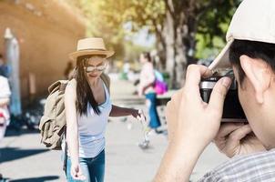 Tourist man taking photo of his friend during walking in a city trip in Chiang Mai, Thailand - young people street travel concept