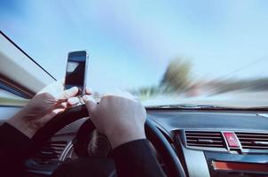 Close up of a man driving car dangerously while using mobile phone photo