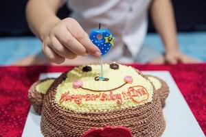 el niño está felizmente soplando velas en su pastel de cumpleaños - concepto de celebración de la fiesta de cumpleaños feliz y alegre foto