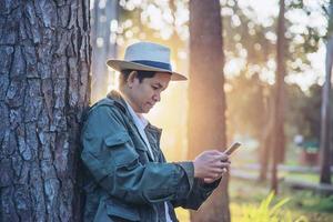 Asian man with mobile phone in forest tree nature - people in spring nature and technology concept photo
