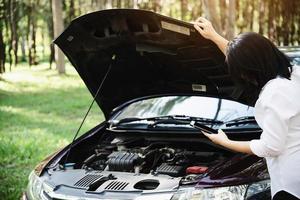 Asian woman calling repairman or insurance staff to fix a car engine problem on a local road - people with car problem transportation concept photo