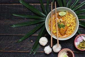 receta de khao soi, khao soi, khao soi kai, fideos tailandeses khao soi, curry de pollo con condimento servido en una mesa de madera foto