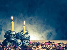 calaveras con velas encendidas y flores secas sobre fondo oscuro.tono vintage foto