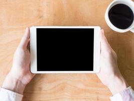 Top view of  male hands using tablet with coffee cup on wooden table. photo