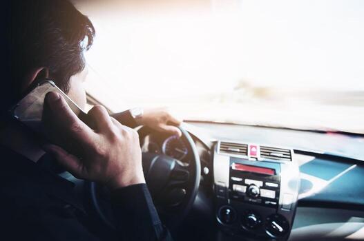Close up of a man driving car dangerously while using mobile phone photo