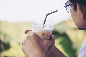 Casual Asian man drink ice coffee happily in nature - people with coffee in nature concept photo