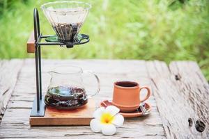 Making drip coffee in vintage coffee shop with green garden nature background - fresh coffee in nature concept photo