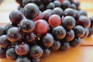 Clusters of ripe purple grapes on wooden background. Pile of fresh red and black grapes as a background. Health Fruits photo
