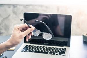 Businessman holding eyeglasses and working on the desk photo