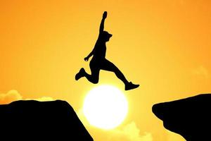 Silhouette of an athlete jumping on a rocky cliff photo