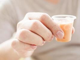 Man showing small glass of ice tea photo