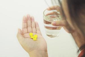 Woman is holding medicine tablets and a glass of water photo