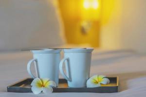 primer plano de una taza de café de bienvenida doble en una cama blanca en la habitación del hotel - hotel bien hospitalidad concepto de viaje de vacaciones