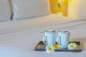 Close up of twin welcome coffee cup on white bed in hotel room - hotel well hospitality vacation travel concept photo