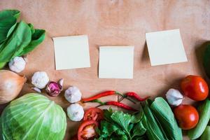 Top view of Fresh vegetables with Blank papers on wooden table background. photo