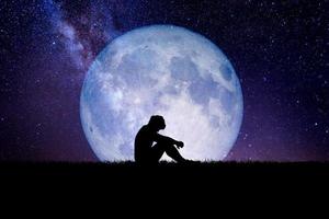 Desperate and lonely man in the background of the moon at night. Desperate, heartbreaking, and lonely concepts photo