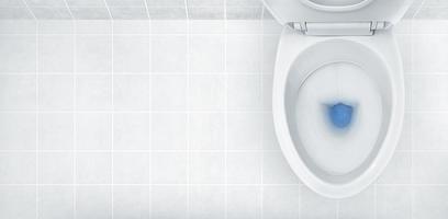 Top view of toilet bowl, blue detergent flushing in it photo