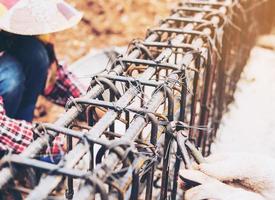 Vintage style photo of construction workers are installing steel rods in reinforced concrete beam