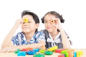 un niño y una niña asiáticos están jugando alegremente a un colorido juguete de bloques de madera foto