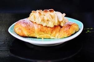Fresh croissant with almonds on the plate photo