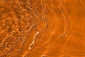 Defocus blurred orange water shining in the sea. rippled water detail background. The water surface in the sea, ocean background. Water wave under sea texture background. photo