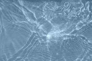 Defocus blurred transparent blue colored clear calm water surface texture with splashes and bubbles. Trendy abstract nature background. Water waves in sunlight with copy space. Blue watercolor texture photo