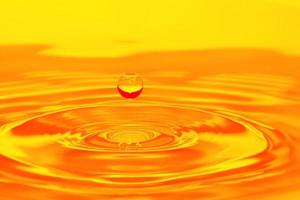 Defocus blurred transparent orange colored clear calm water surface texture with splashes and bubble. Trendy abstract nature background. Water wave in sunlight with copy space. Orange water drop color photo