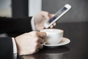 hombre de negocios usando teléfono móvil mientras bebe café en una cafetería - hombre de negocios de estilo de vida moderno en el concepto de cafetería foto