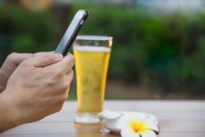 Man using mobile during happy time relax in restaurant with softdrink and green garden background - people relax with technology lifestyle concept photo