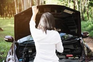 mujer asiática que llama al reparador o al personal de seguros para solucionar un problema de motor de camión en una carretera local - personas con concepto de transporte de problemas de camión foto