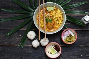 receta de khao soi, khao soi, khao soi kai, fideos tailandeses khao soi, curry de pollo con condimento servido en una mesa de madera foto