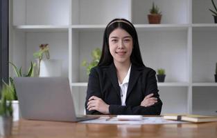 Charming Asian woman working at the office using a laptop Looking at the camera. photo