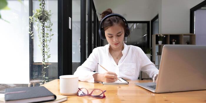 close up of Student learning online class by using laptop computer and writing notebook at workplace, E learning and online working concept. photo