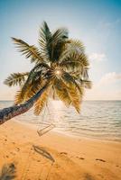 paisaje de puesta de sol de playa tropical con columpio de playa o hamaca y cielo de puesta de sol arena blanca y mar tranquilo para pancarta de playa. perfecto concepto de vacaciones de playa y vacaciones de verano. impulsar el proceso de color foto