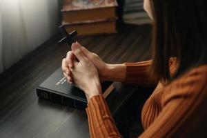 mujer sentada y estudiando las escrituras. la cruz de madera en las manos. conceptos de educación cristiana las sagradas escrituras se abren y oran a dios. foto