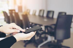 Man using mobile over blurred empty business meeting room photo