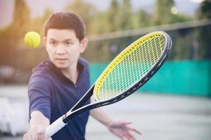 hombre que sostiene la raqueta a punto de golpear una pelota en la cancha de tenis - gente en el concepto de partido de tenis