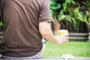 Man drink ice mango orange blend in green garden - relax people with cold fruit drink concept photo