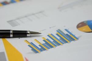 Business document reports graphics and charts and pen on paperwork financial statistics growth investment account planning analysis at office. photo