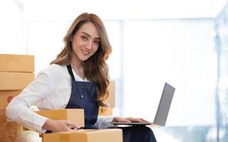 Retrato de mujer joven asiática SM trabajando con una caja en casa el lugar de trabajo.Propietario de una pequeña empresa de inicio, pequeña empresa emprendedora o empresa independiente en línea y concepto de entrega. foto