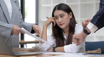 A male boss complains to a tired and bored young Asian female accountant or female financial worker in the office. photo