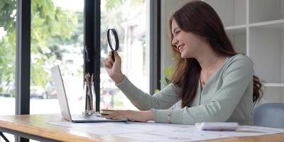 Business analyst using magnifying to review financial graphs, charts. Concept of Analyze return on investment and business analytics growth. photo