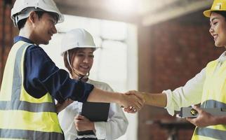 Male civil engineer or architect hand shake with contractor after discussing about designing of building styles and inspect progress of housing project at construction sites. photo