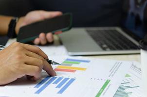 businessman holding pen to work computer graphs and charts data statistical data financial analysis documents. photo