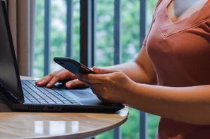 Businessman hand holding mobile smartphone digital marketing online technology and communication social network with computer laptop internet browsing and shopping online on desk concept. photo