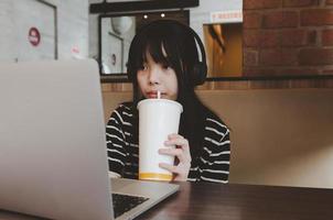 adolescentes con auriculares viendo películas en las redes sociales o estudiando en línea bebiendo agua y relajándose en el sofá. foto