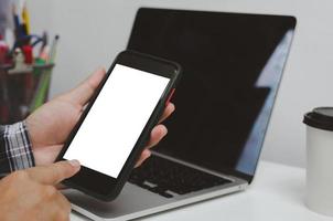 hombre de la mano que sostiene la tecnología digital de la red de teléfonos inteligentes móviles en línea maqueta pantalla blanca. foto