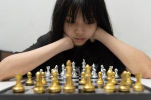 linda jovencita jugando al ajedrez usando su mente. foto