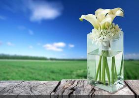jarrón de vidrio con hermosas flores blancas en el suelo de madera, imagen sobre fondo natural para el diseño foto